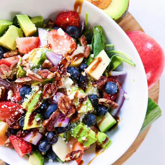 Berry pecan arugula and spinach salad in a bowl.