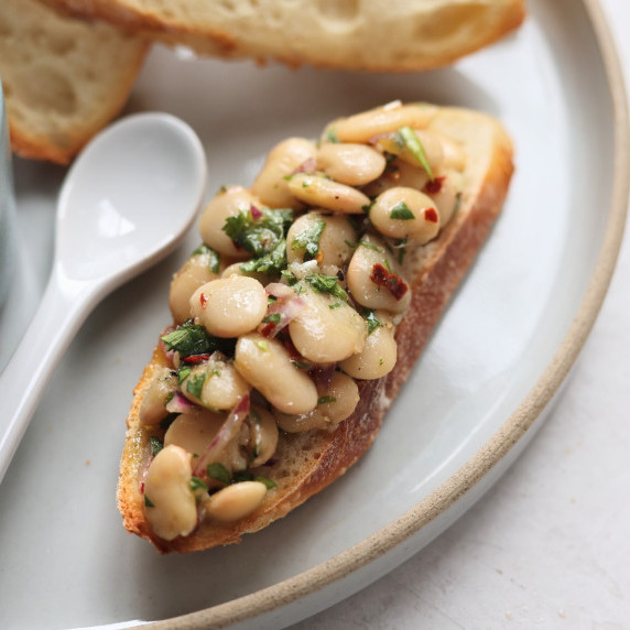marinaded white beans on toast on gray plate 