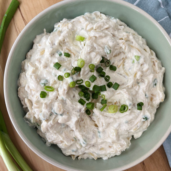 Onion dip in a light blue bowl garnished with green onion.