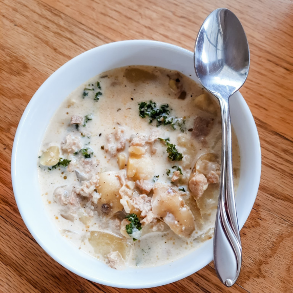 Bowl of Zuppa Toscana on a table with a spoon