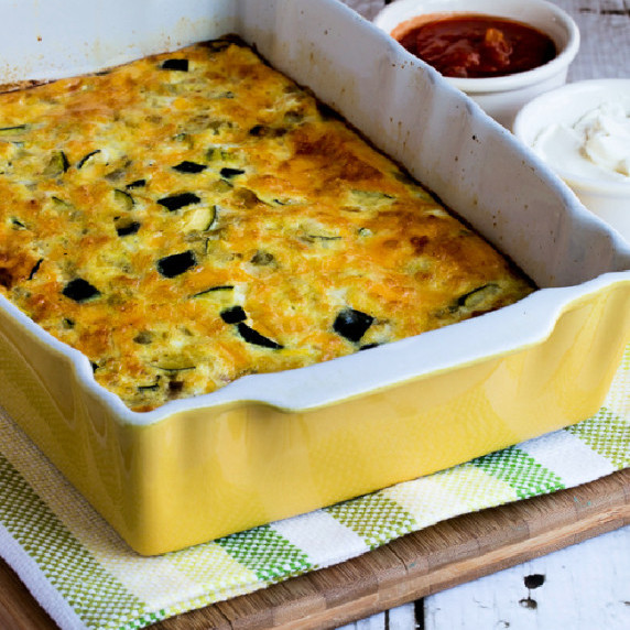 Zucchini and Green Chile breakfast casserole shown in baking dish with sour cream and salsa on the s