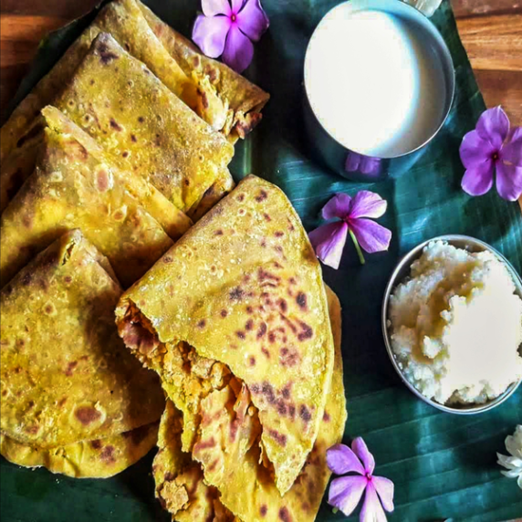 Traditional Indian sweet flatbread - Puranpoli served with homemade ghee and milk on a banana leaf.
