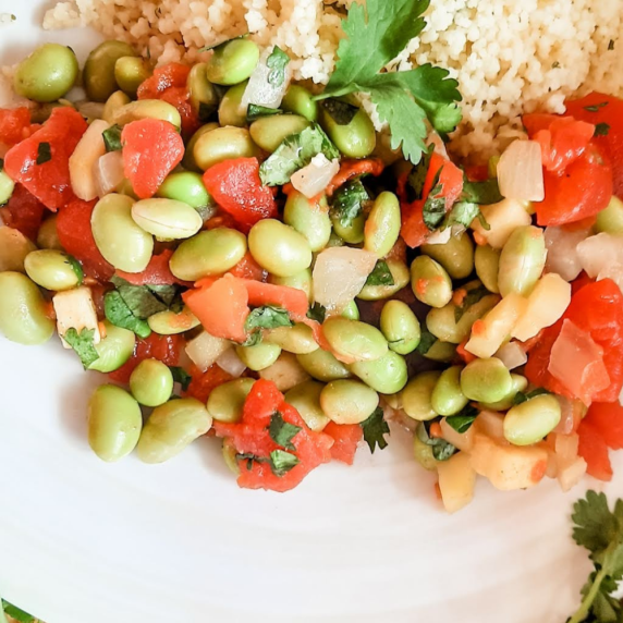 Edamame protein bowl displayed on a white dish next to couscous