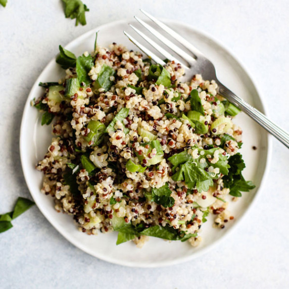 Simple detox quinoa salad on small white plate with fork, on light blue and white surface