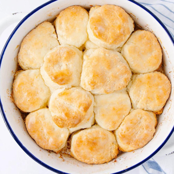 A white round baking dish filled with golden-brown biscuits, arranged closely together.