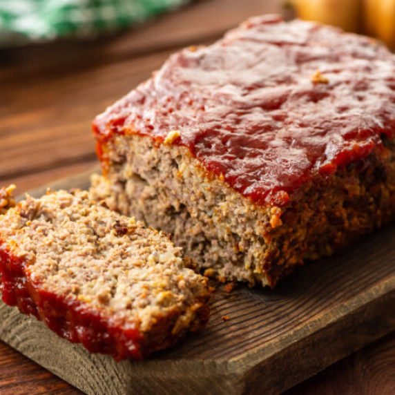 a cooked meatloaf with a slice taken out that shows a ketchup topping.