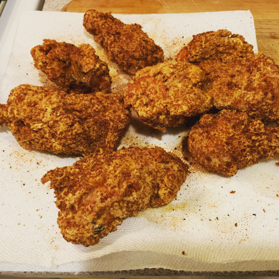 Pieces of fried chicken resting on a paper towel covered plate