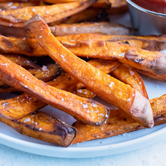 Air Fryer Sweet Potato Fries RECIPE served on a white plate with a side of sauce.