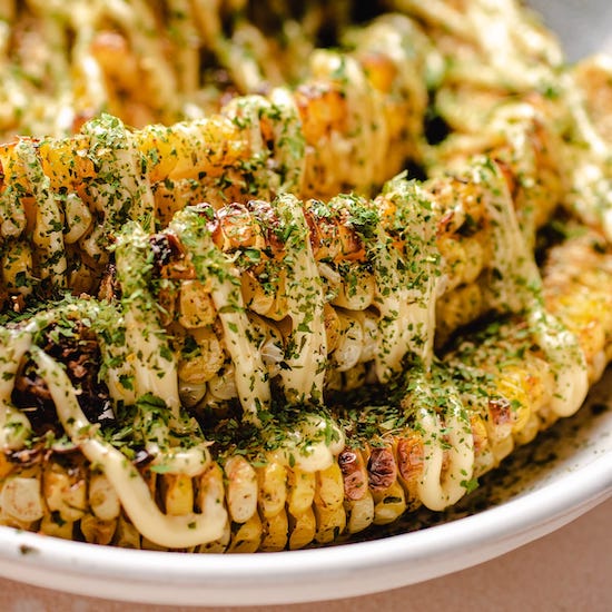 Air fried corn ribs with parsley and mayo in a white bowl