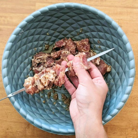 all-purpose marinated pork being skewered over a bowl