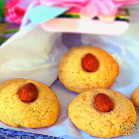 Almond biscuits garnished with raw almonds on paper with a decorative pink box
