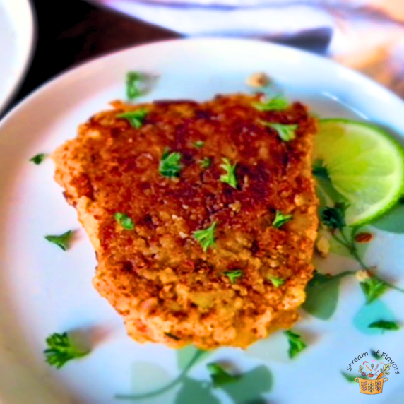 Pan-fried Almond Crusted Cod with lemon juice, garlic, and paprika on a white plate with lime wedge
