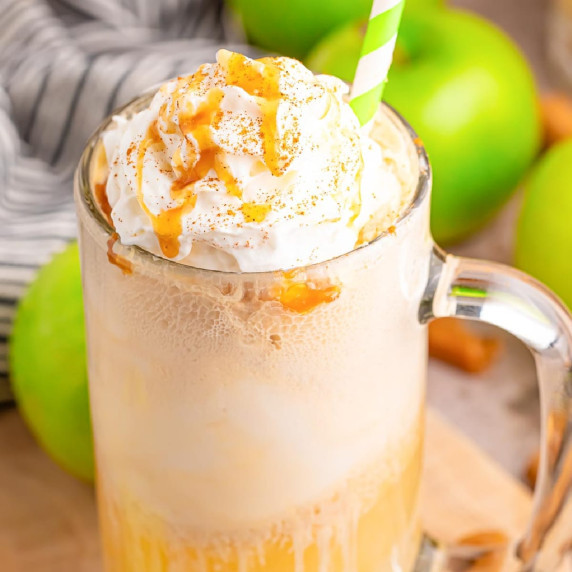 A mug filled with a creamy beverage topped with whipped cream and caramel drizzle.