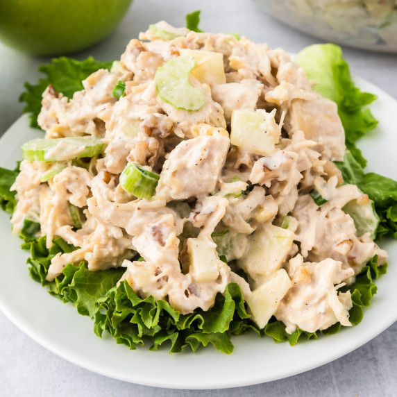 Apple walnut chicken salad piled high on a piece of lettuce on a plate.