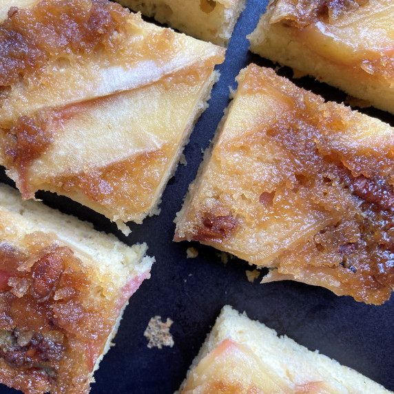 Slices of apple walnut snack cake on a black cutting board.