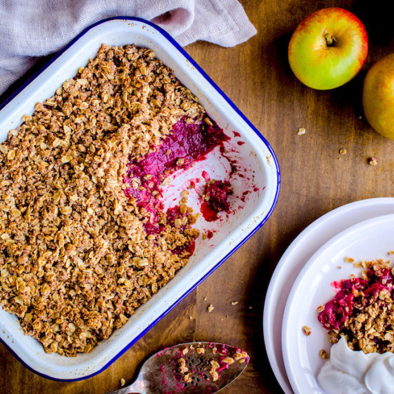 Overhead image shows an enamel tray of apple and blackberry crumble with the pink filling visible.