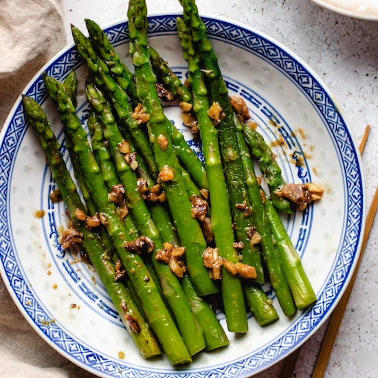 Asparagus with miso butter on a white plate with a blue border