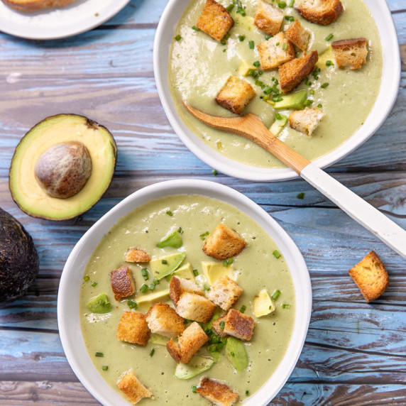 Two bowls of chilled soup with croutons on top.