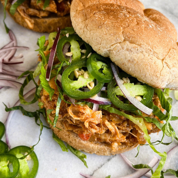 BBQ pulled chicken on a bun with shredded lettuce, sliced red onion and jalapenos..