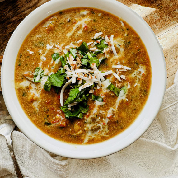 chickpea curry soup in a bowl topped with toasted coconut shreds and cilantro