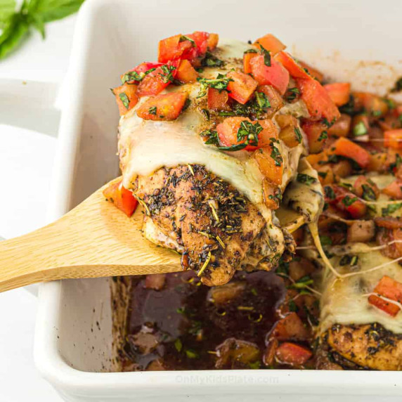 Bruschetta chicken being lifted from a pan with a spoon
