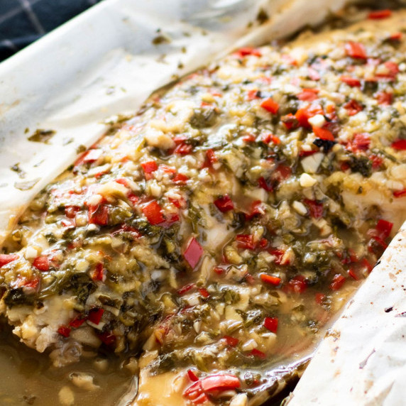 A piece of barramundi coated in thai sauce inside a parchment paper parcel.