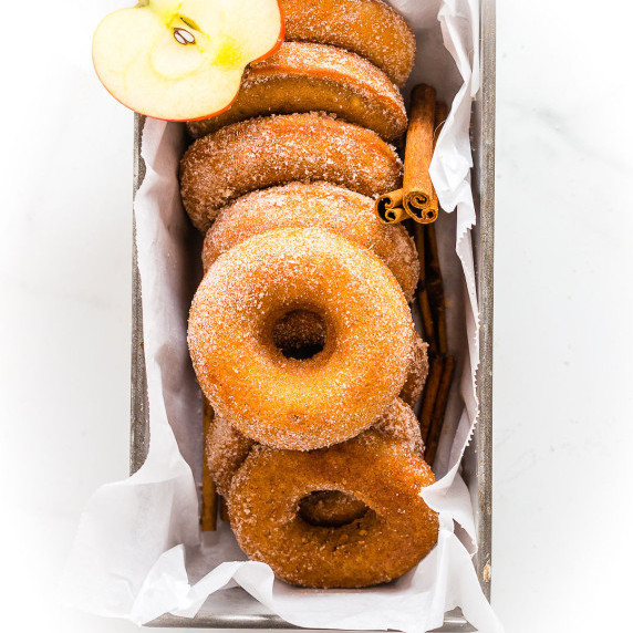 apple cider donuts in a serving pan with an apple cut in half