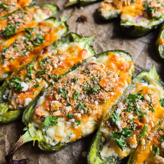 A tray of cheesy jalapenos topped with a golden crumb topping & green parsley