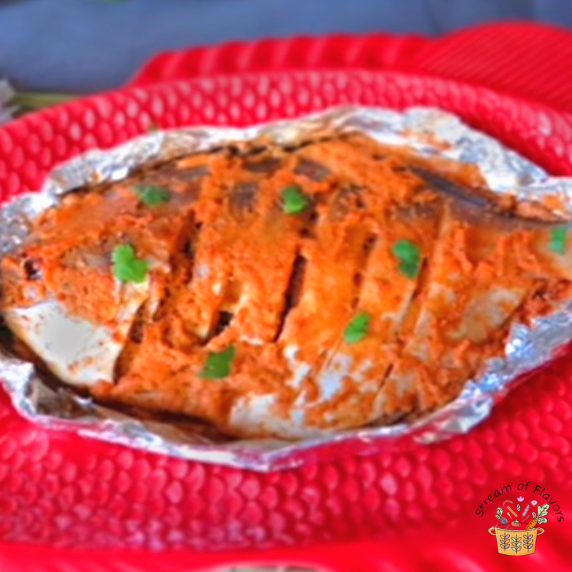 Baked pomfret in foil on a red fish plate