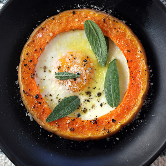 Eggs baked in roasted butternut squash rings, garnished with sage and Parmesan.