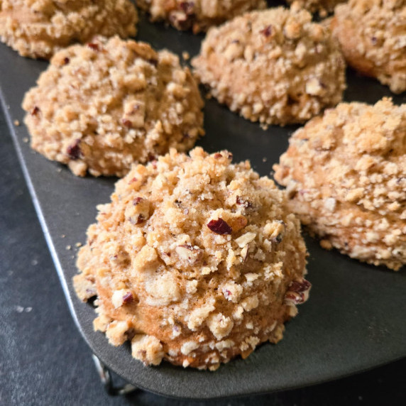 A muffin tin full of golden brown banana crumble muffins