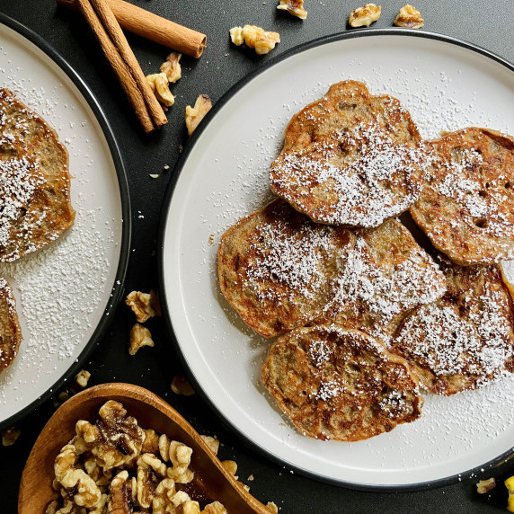 Banana fritters dusted with powdered sugar on white plates. 