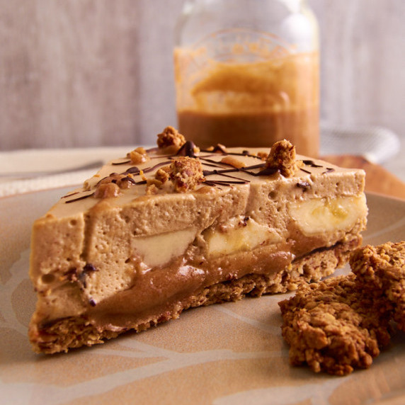 A piece of banoffee Protein Mousse pie with pieces of almond crust scattered around and over