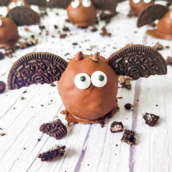 Chocolate covered Oreo ball on a counter decorated to look like a bat with cookies and chocolate.
