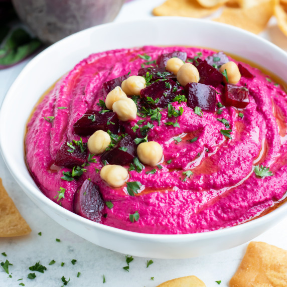 Roasted Beet Hummus RECIPE in a white bowl with roasted beets and chickpeas on top.