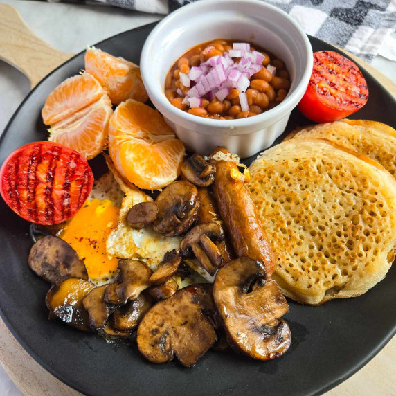 Loaded breakfast plate featuring loads of brown foods, purple onions, and bright red tomatoes.