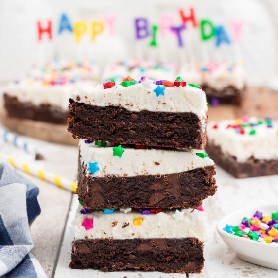 stack of birthday brownies with candles in the background