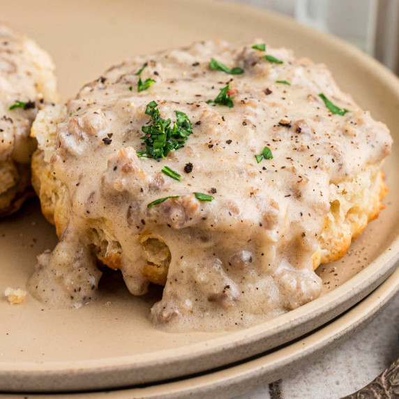 Close up of a biscuit with sausage gravy on top.