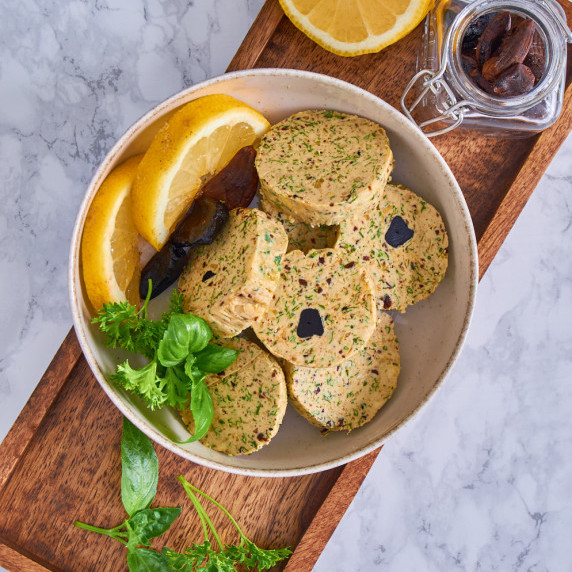 A dish with round slices of Black Garlic Butter with lemon, the cross section visible.