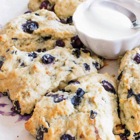 Blueberry scones with small bowl of icing for drizzling on scones. 