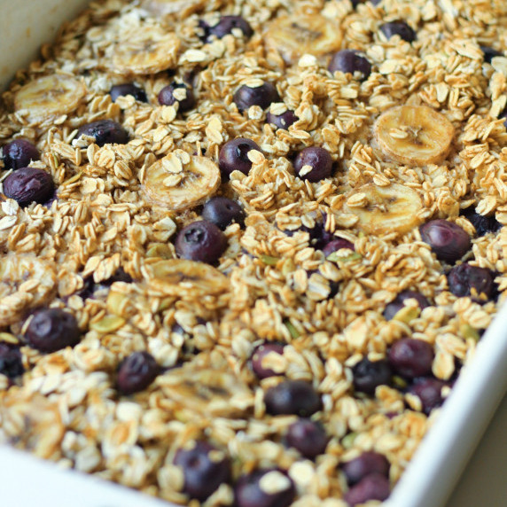 vegan blueberry banana baked oatmeal with bananas and blueberries on a white plate