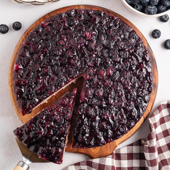 Blueberry upside-down cake with a glossy blueberry topping and one slice removed.