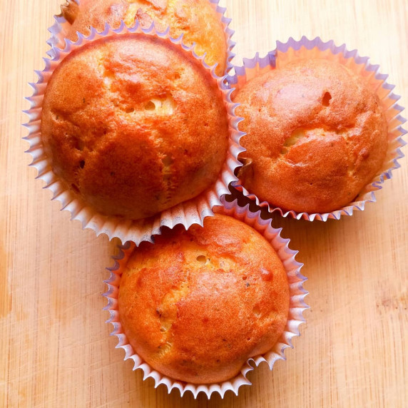 Golden breakfast muffins in paper liners, showcased from above on a wooden surface.