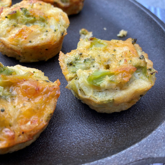 Broccoli and cheese baked muffin bite on a gray platter. 