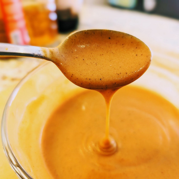 maple brown butter hot sauce on a spoon drizzling into the bowl