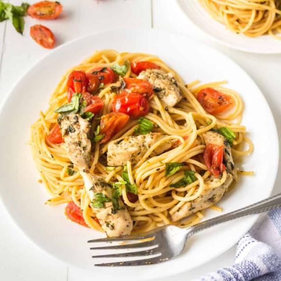 Plate of bruschetta chicken pasta with tomatoes and basil.