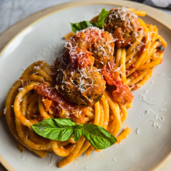 Two gorgeous pasta nests topped with sausage meatballs, red arrabbiata sauce, and fresh green basil