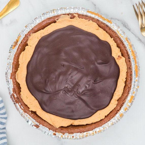 A buckeye pie in a foil container with a peanut butter filling and a layer of chocolate on top.