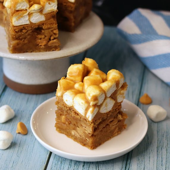 Butterbeer blondie on a white plate on a wooden table with more blondies in the background