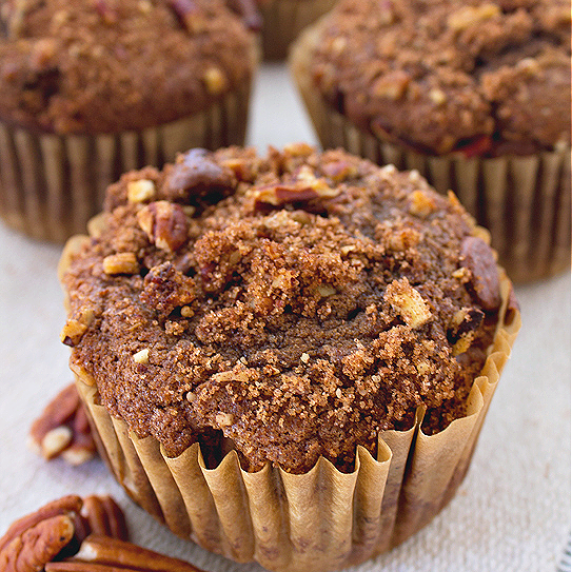 Chocolate muffins with chocolate chips on top and pecans lying next